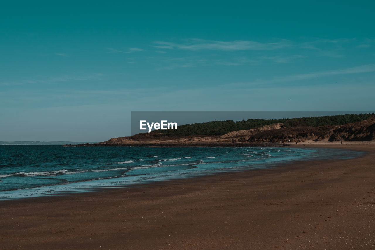 Scenic view of beach against blue sky