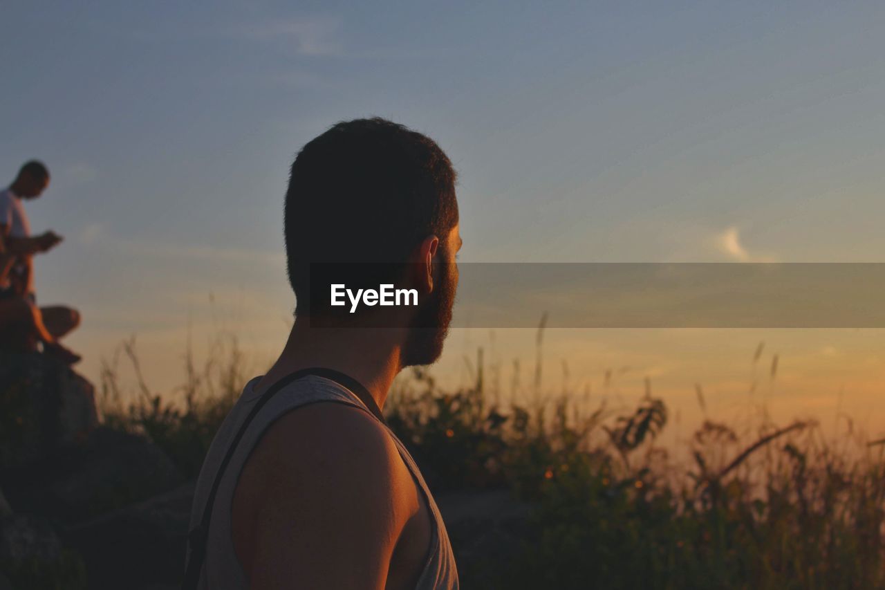 Side view of man standing against sky during sunset