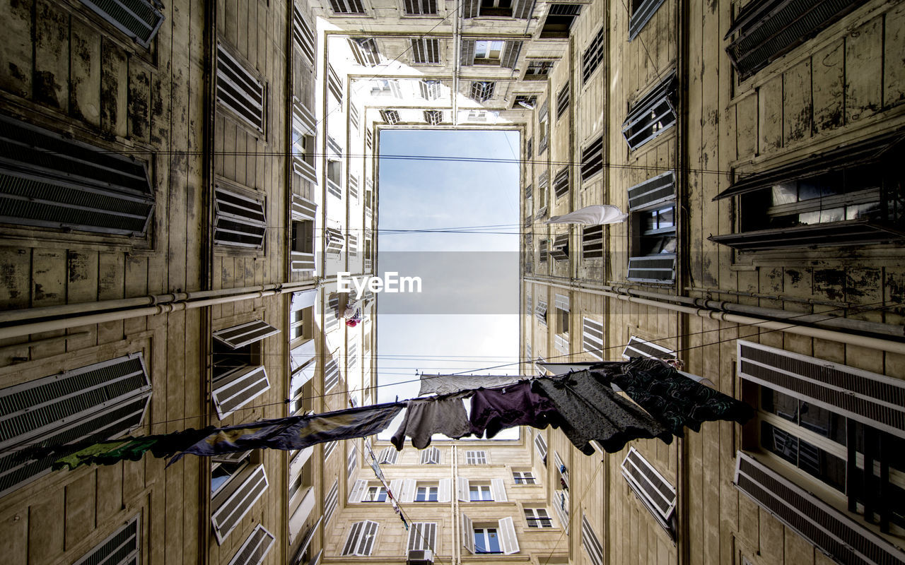 Directly below shot of clothes hanging amidst buildings against sky