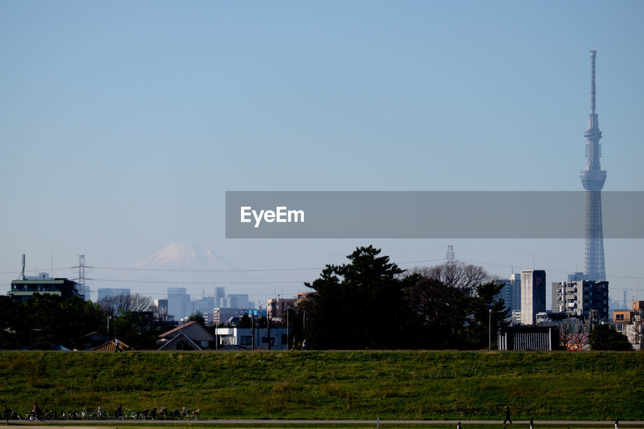 Scenic view of grassy field and buildings against sky