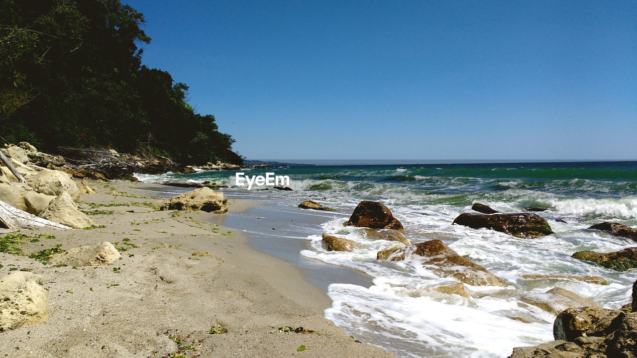 Scenic view of beach against clear blue sky