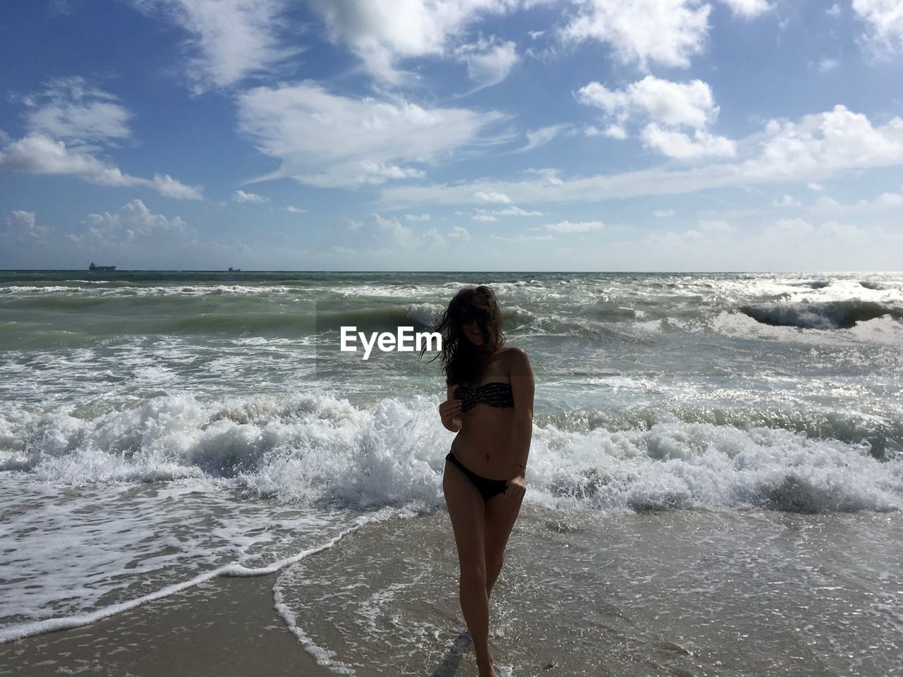 Woman wearing bikini while wading in sea against sky