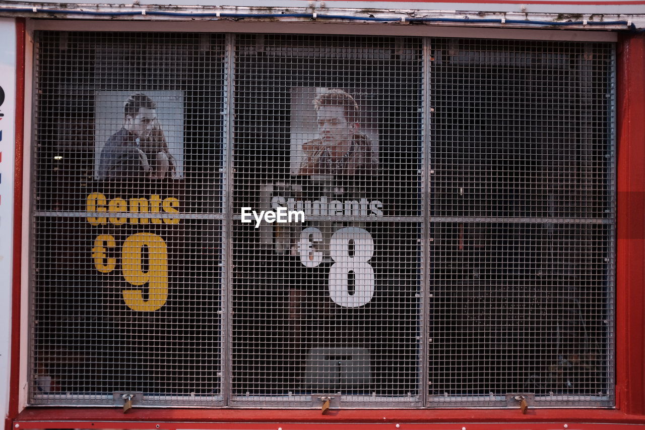 Text and numbers at barber shop seen through closed shutter