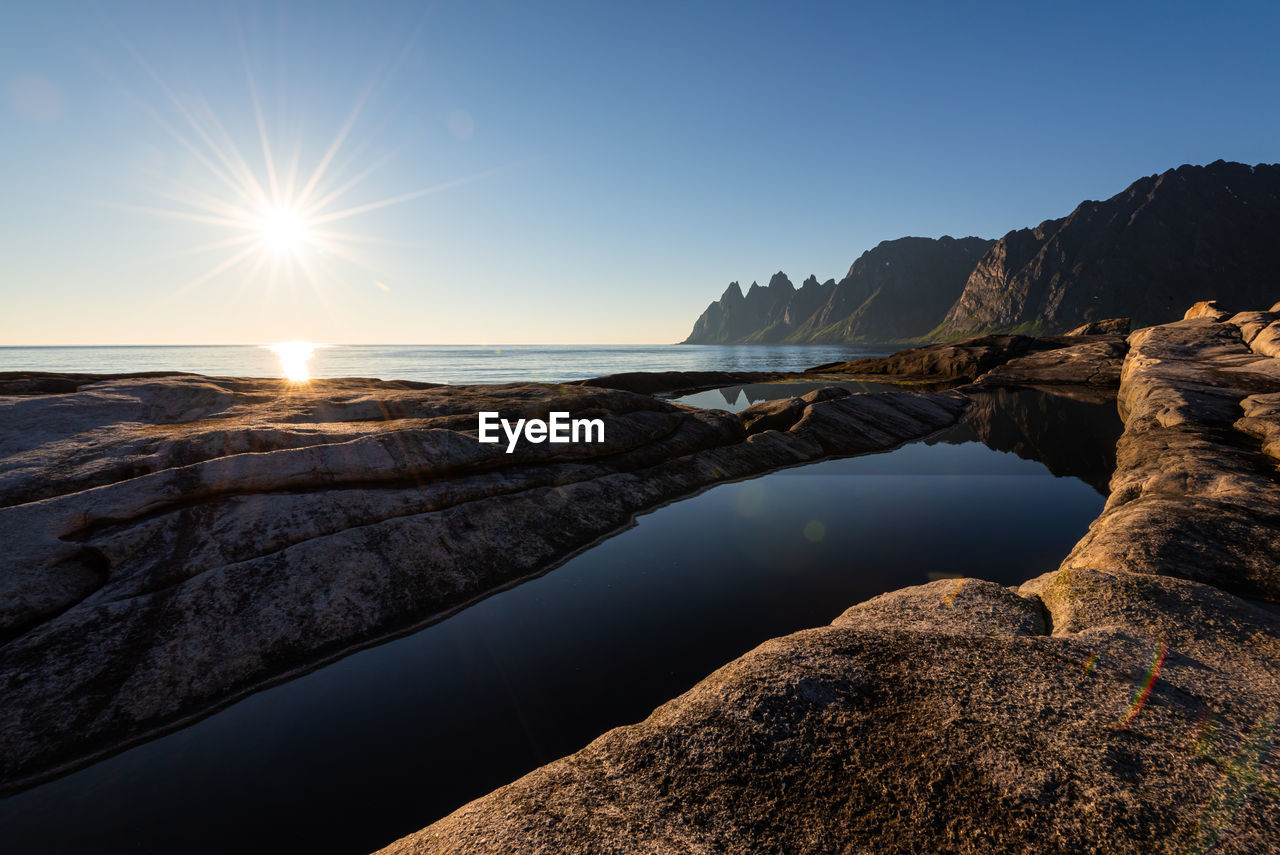 Midnight sun over cliffs of tungeneset on senja in northern norway at a warm calm summer night