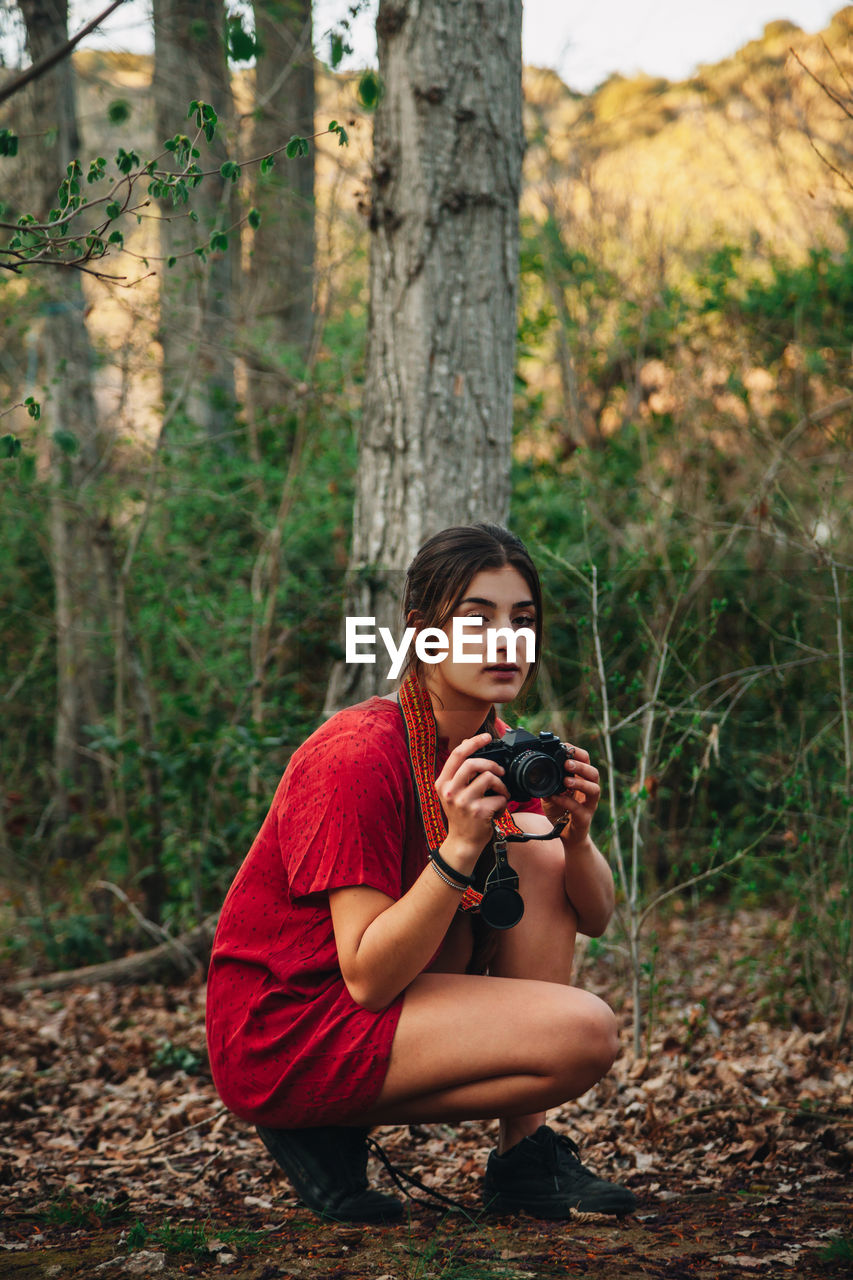 Young woman photographing in forest