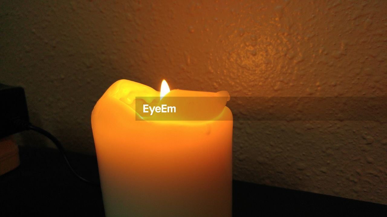 CLOSE-UP OF LIT CANDLES IN DARK ROOM