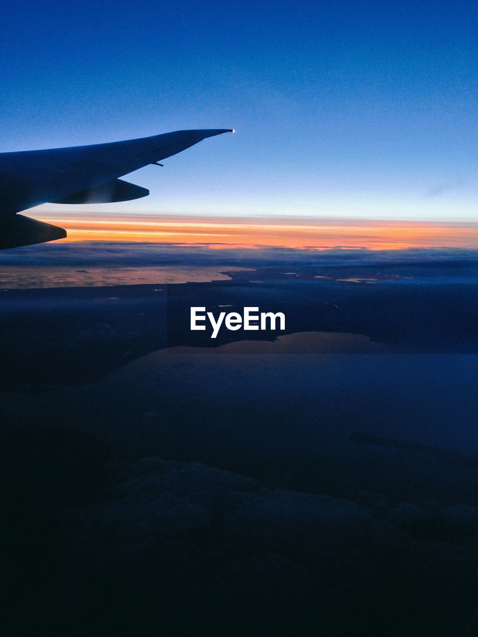 CROPPED IMAGE OF AIRPLANE WING OVER SEA