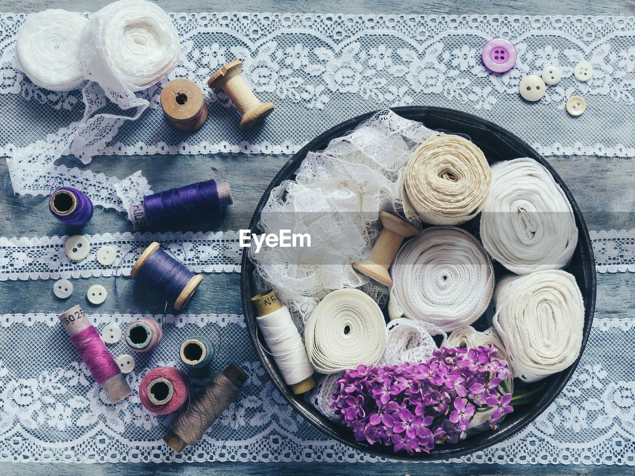 Directly above view of sewing items with purple lilac flowers on table