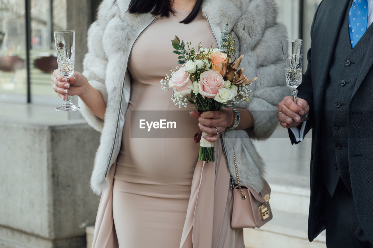Midsection of pregnant woman holding flower bouquet