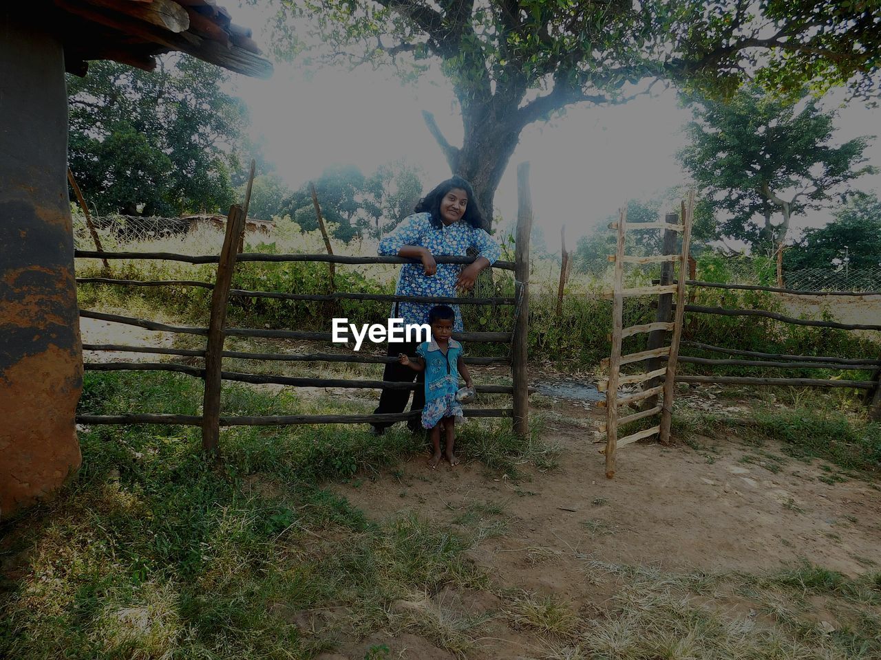 Portrait of mother and daughter standing by fence