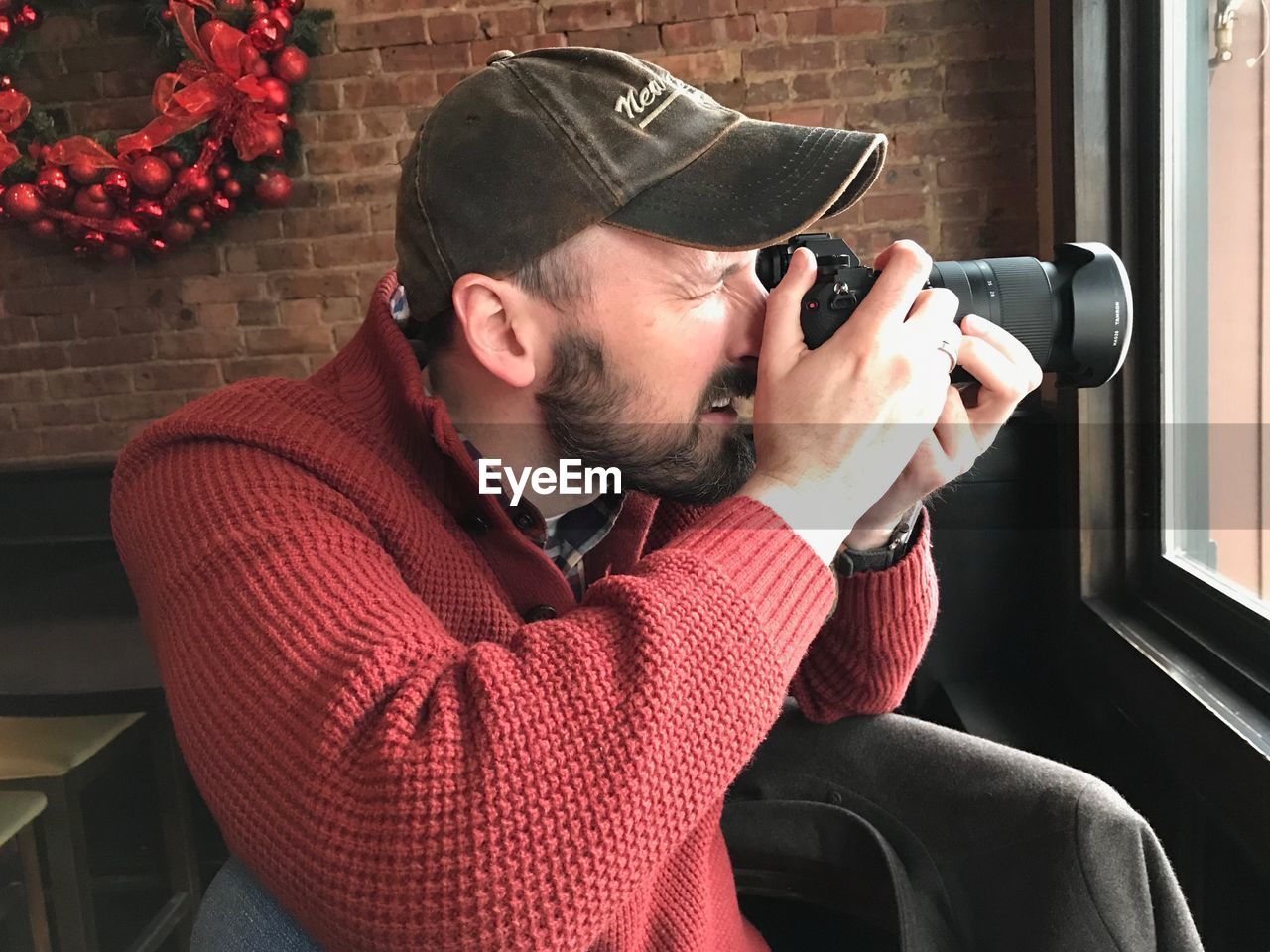 Man photographing with camera by window