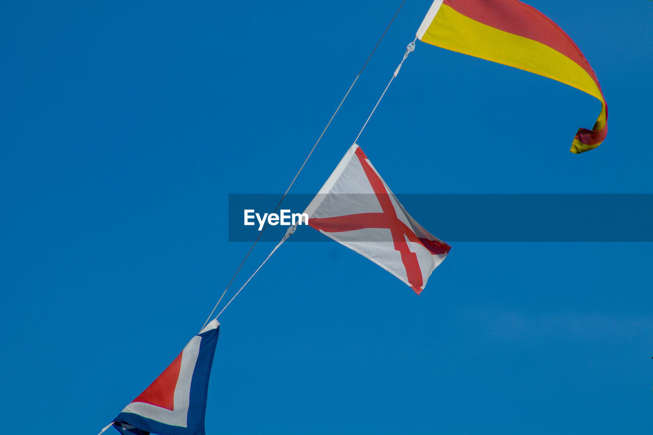 Low angle view of flags against blue sky