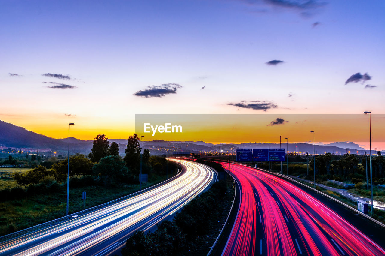High angle view of light trails on highway at sunset