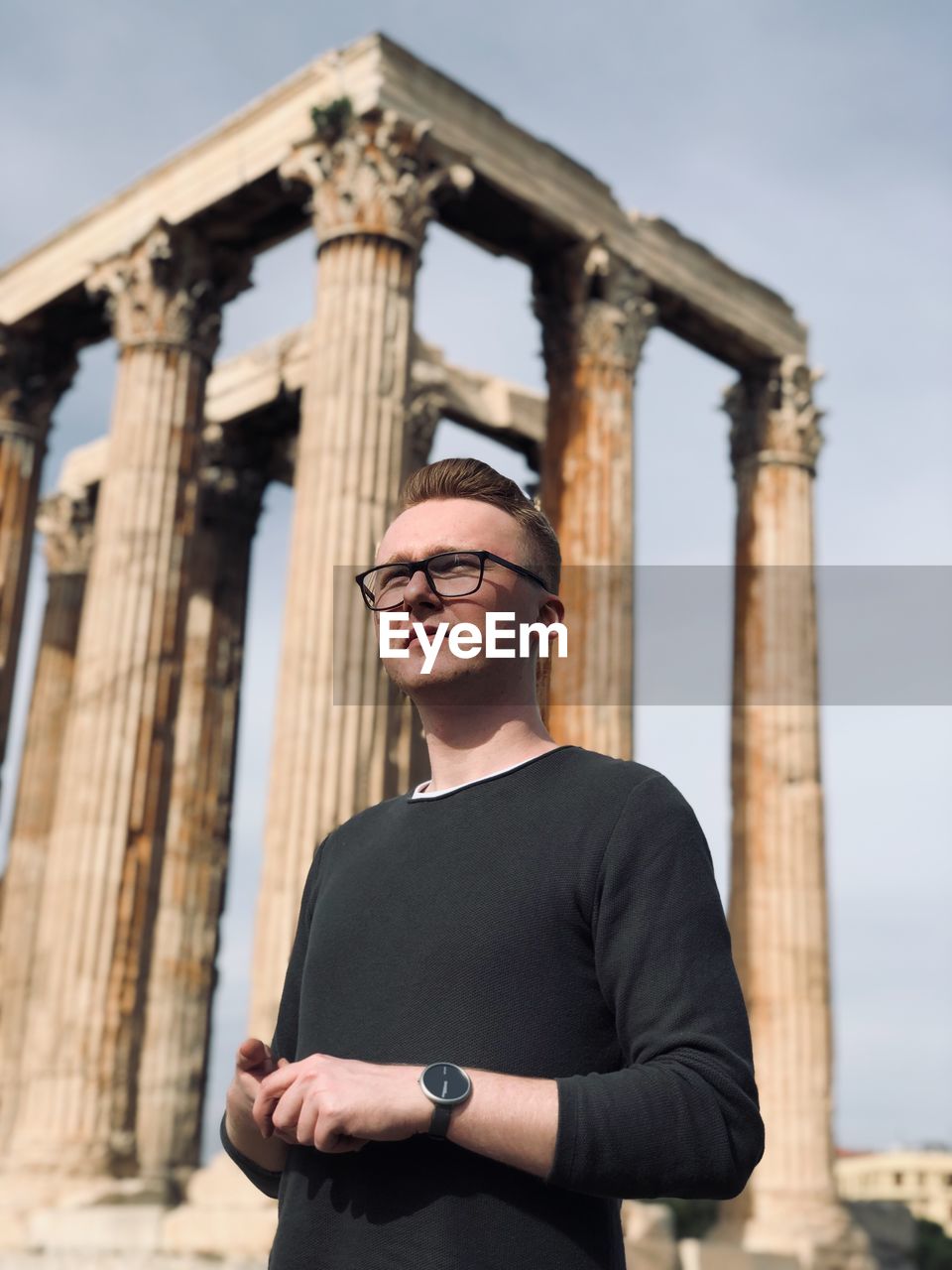 Low angle view of young man standing against old ruin