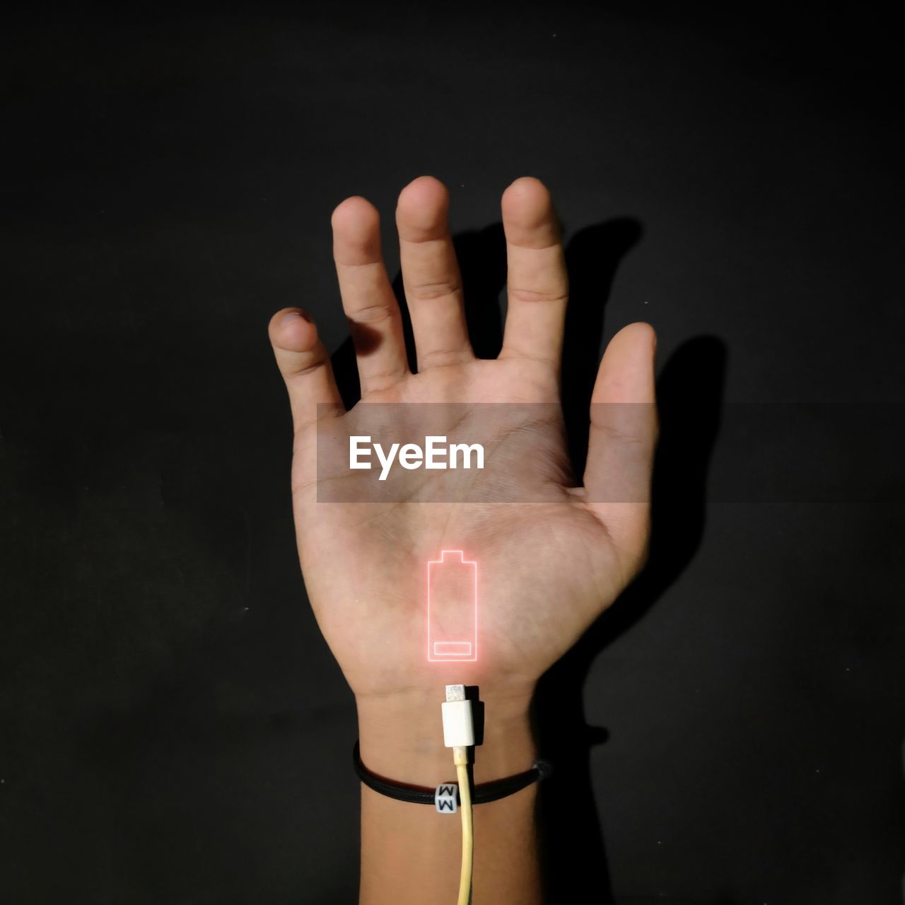 Cropped hand of man with low battery indication against black background