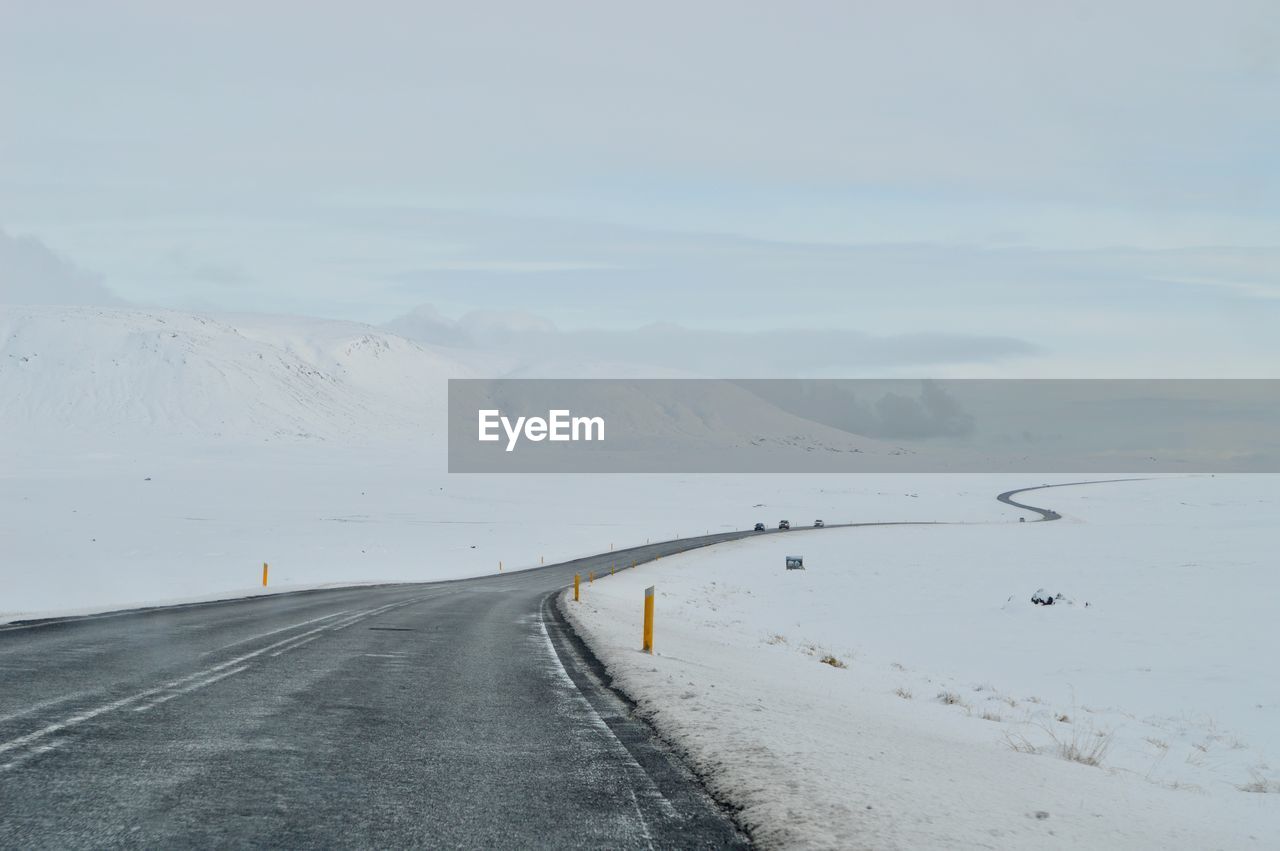 ROAD BY SNOWCAPPED MOUNTAINS AGAINST SKY