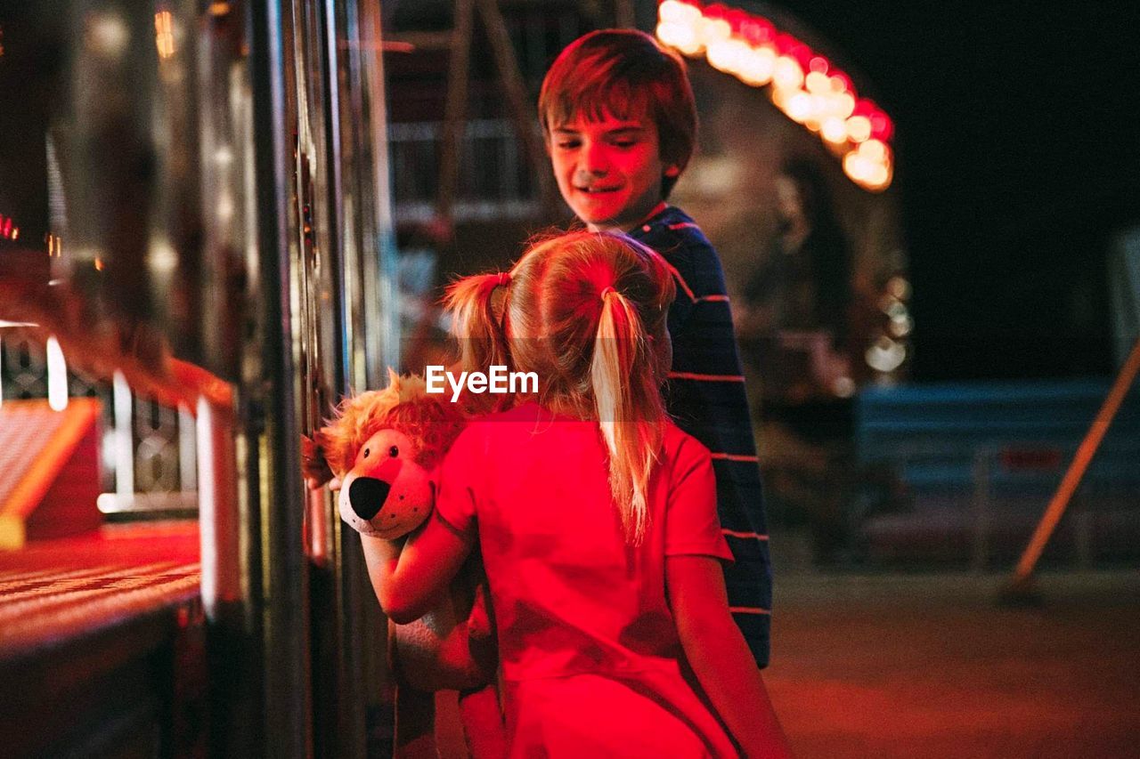 Siblings standing outdoors at night