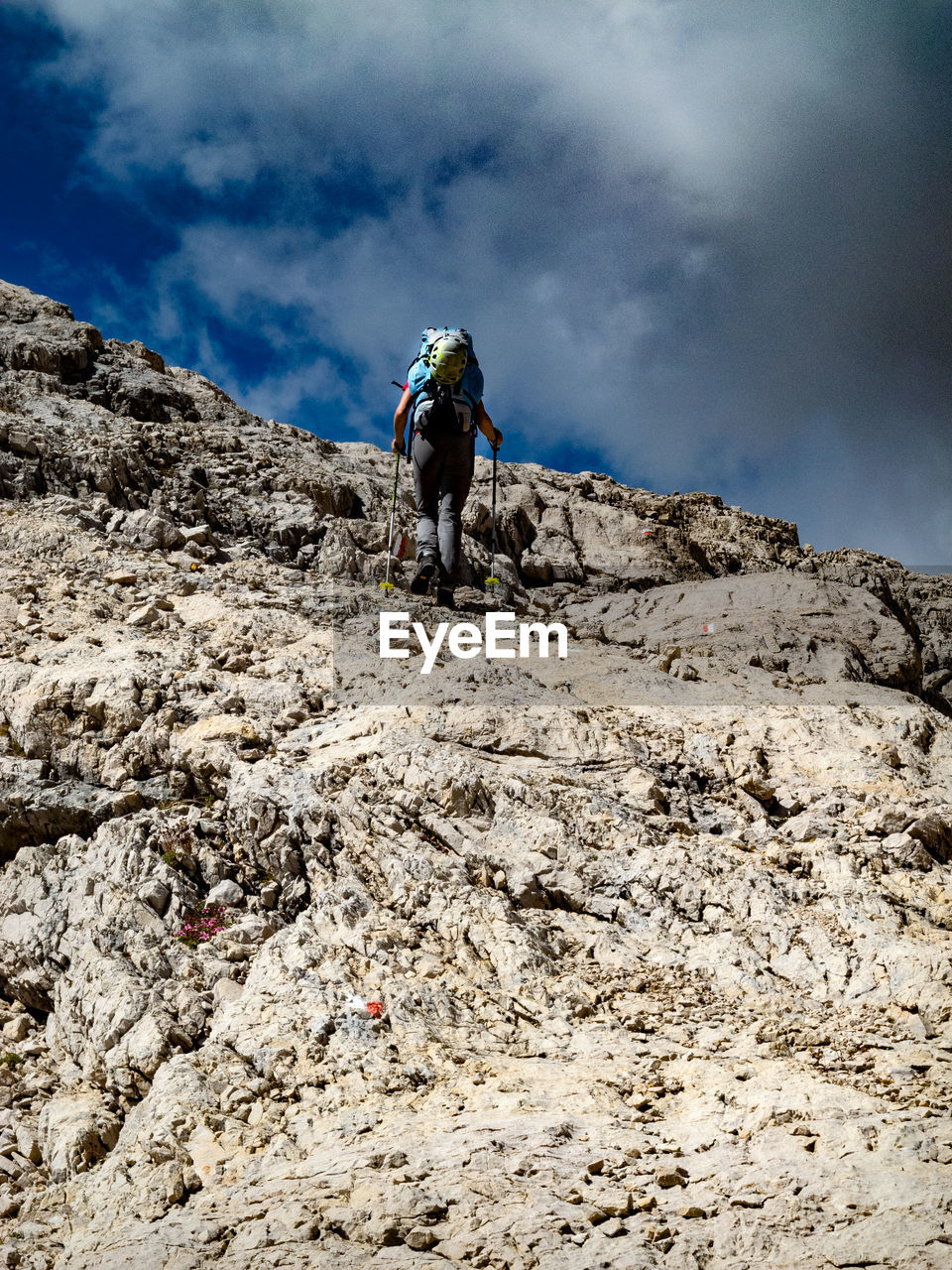 Female backpacker climbing on mountain against sky