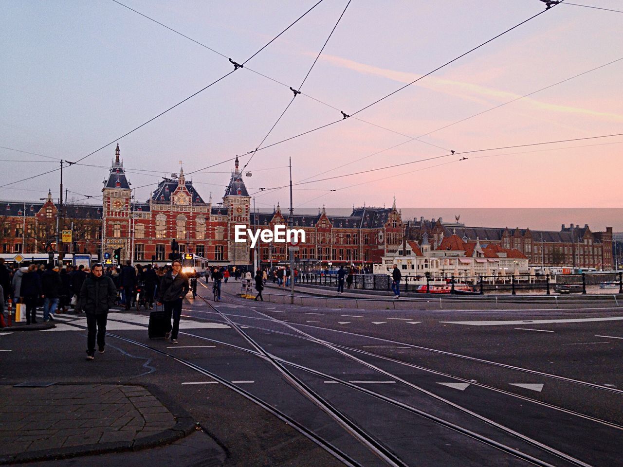 PEOPLE AT RAILROAD STATION AGAINST SKY DURING SUNSET