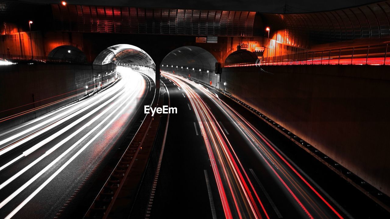 LIGHT TRAILS ON ROAD IN ILLUMINATED TUNNEL