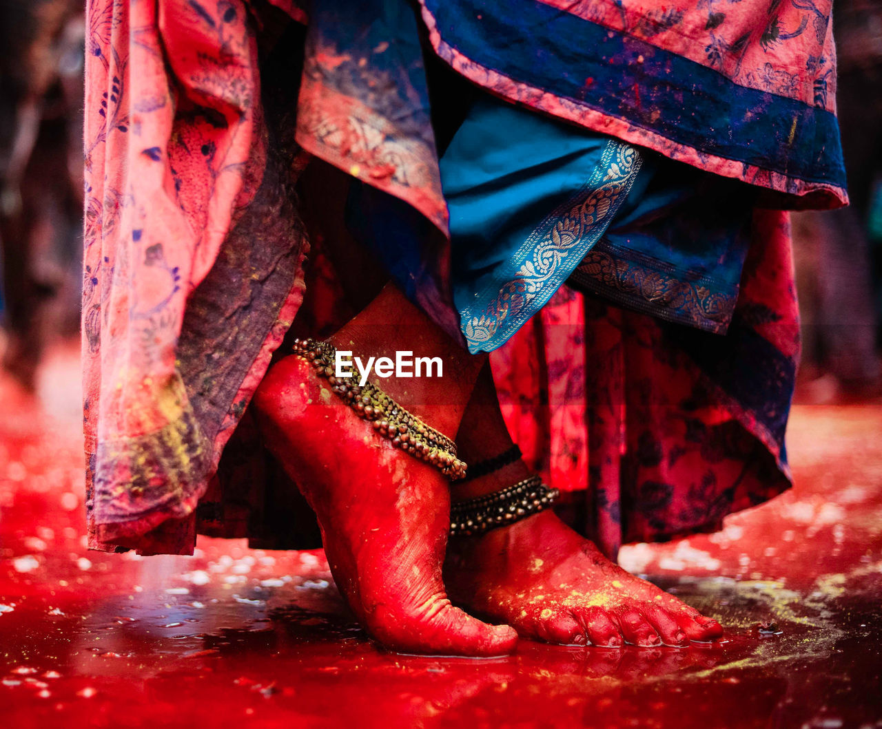 Red feet of woman standing at holi played in radha rani temple barsana, uttarpradesh, india