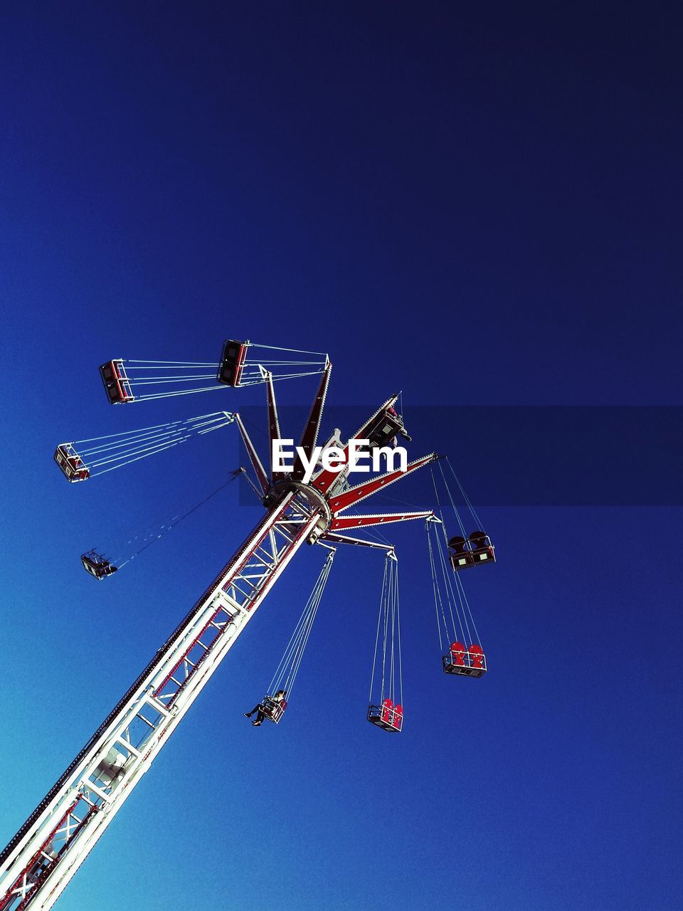 Low angle view of chain swing ride against blue sky