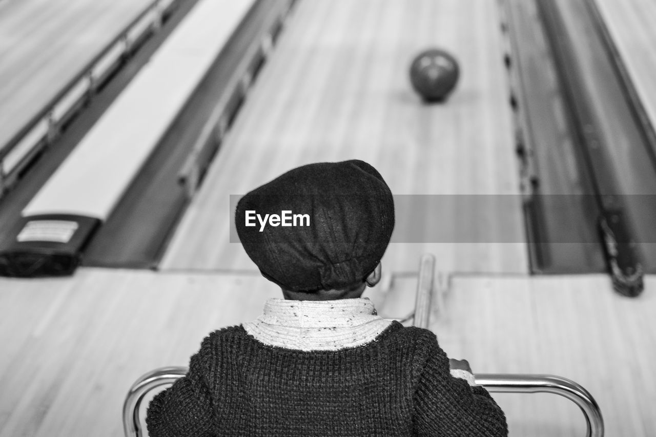 Rear view of boy standing in bowling alley