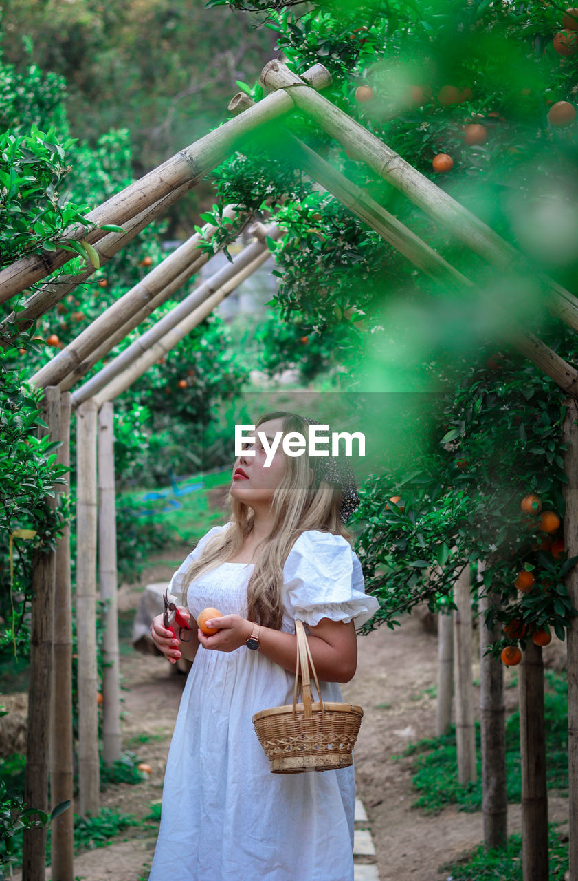 Portrait of smiling young woman standing against trees