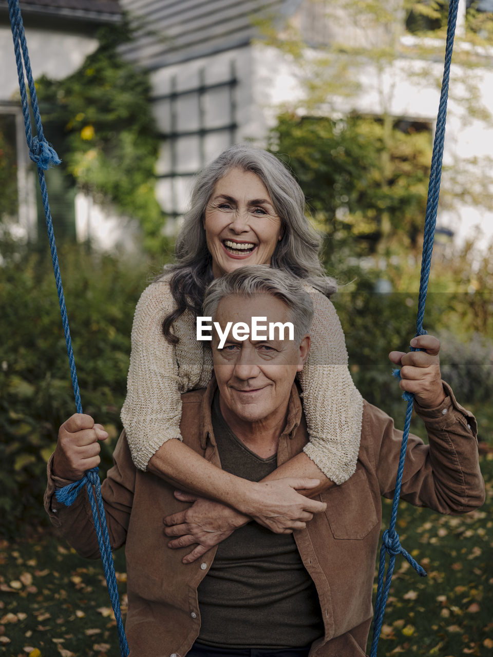 Happy woman embracing senior man on a swing in garden