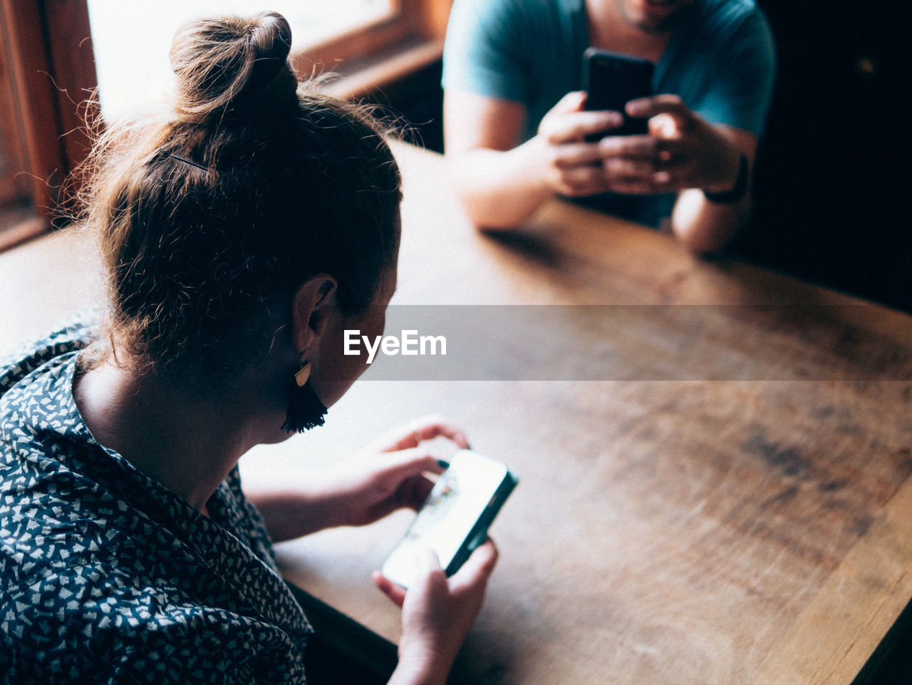 Woman and man using phone at table in bar