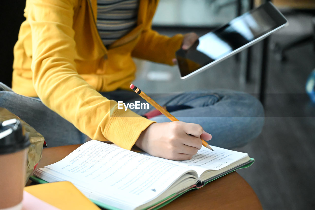 Midsection of woman writing in diary