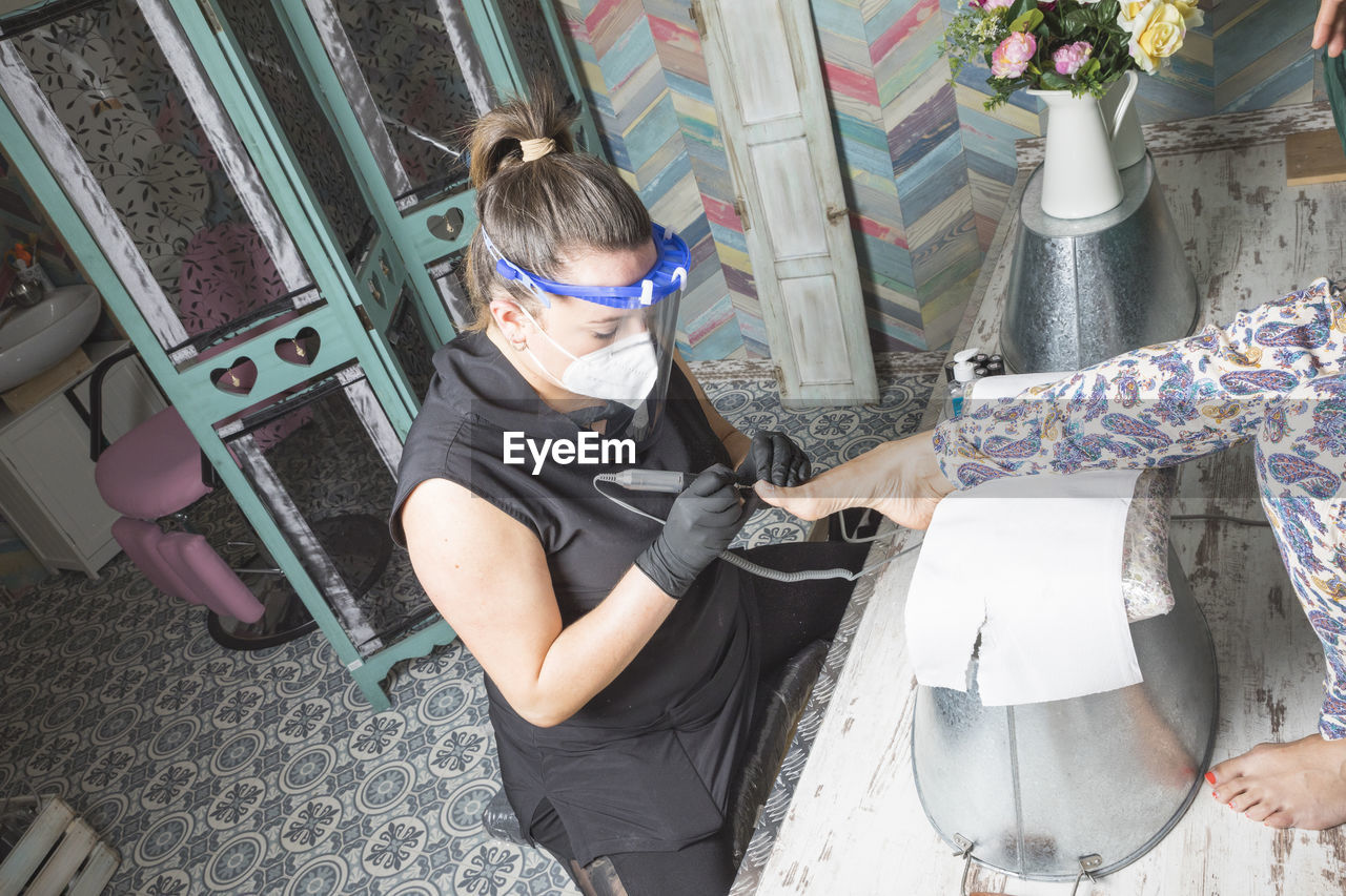 Beautician working with mask and protective screen for the virus covid