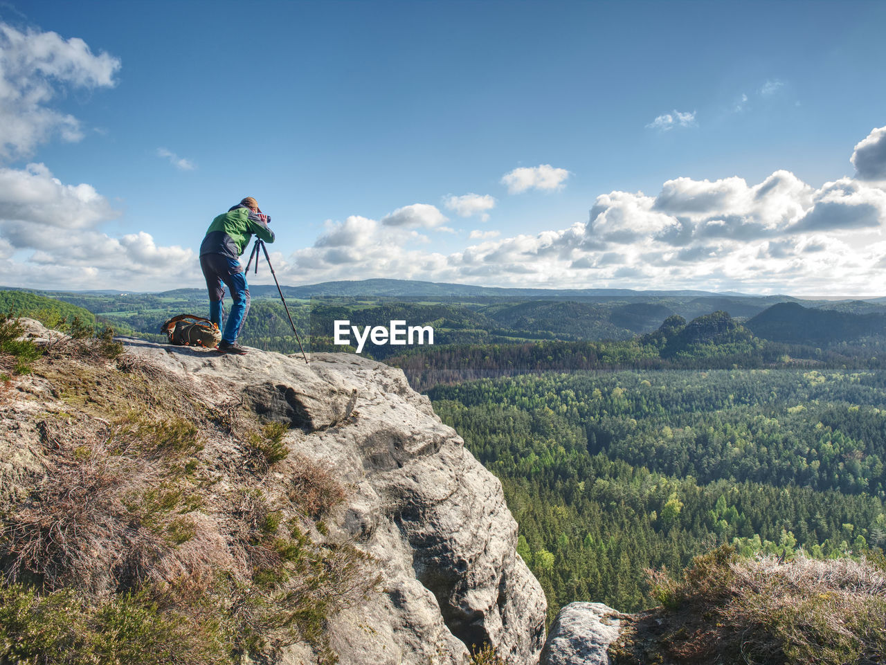 Photographer taking picture of landscape when set tripod at mountain peak. travel hobbies concept