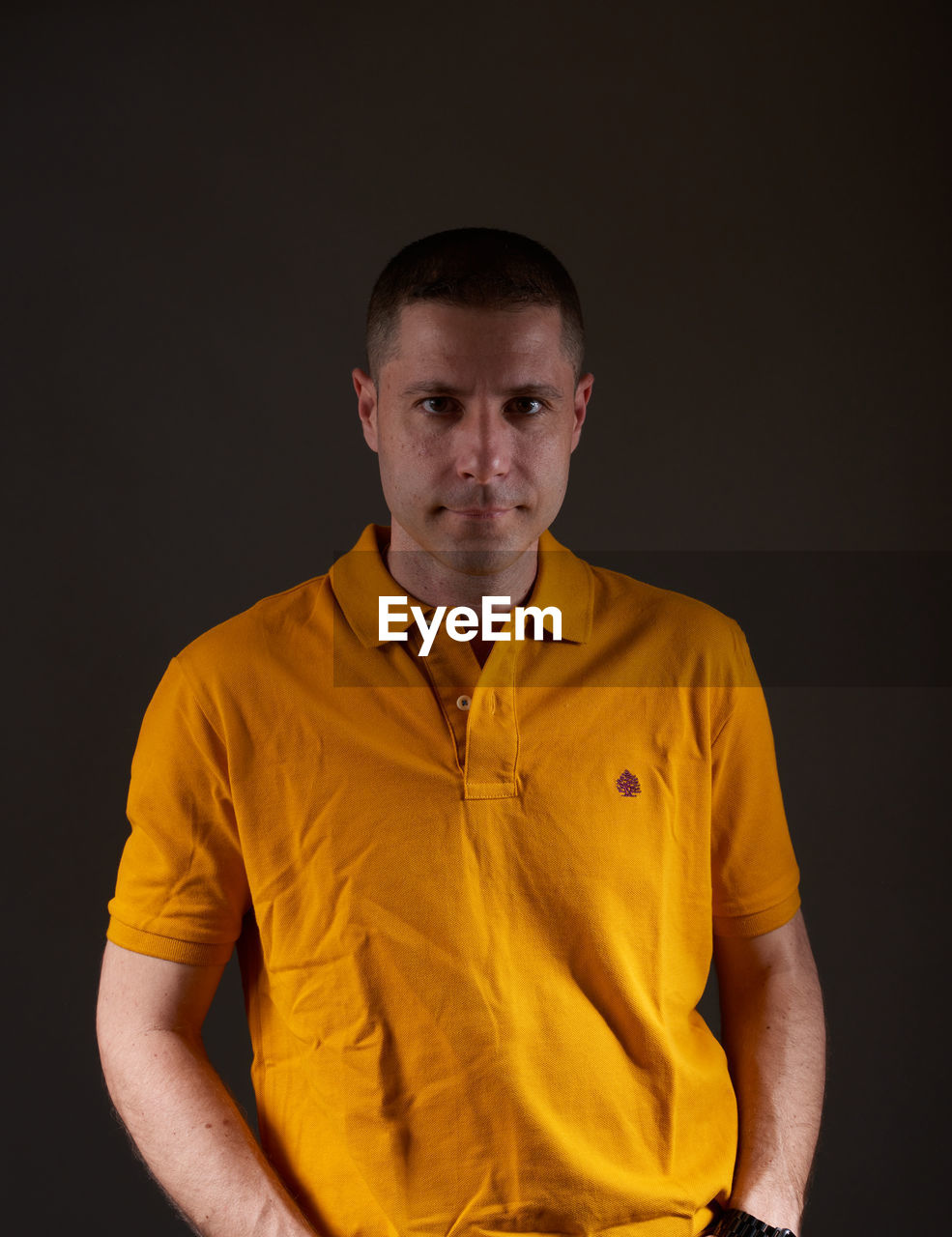 Portrait of young man standing against black background