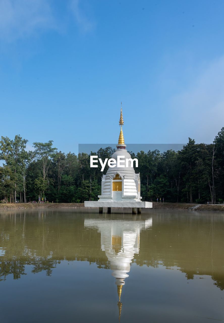 Reflection of buddhist stupa in a  lake against blue sky