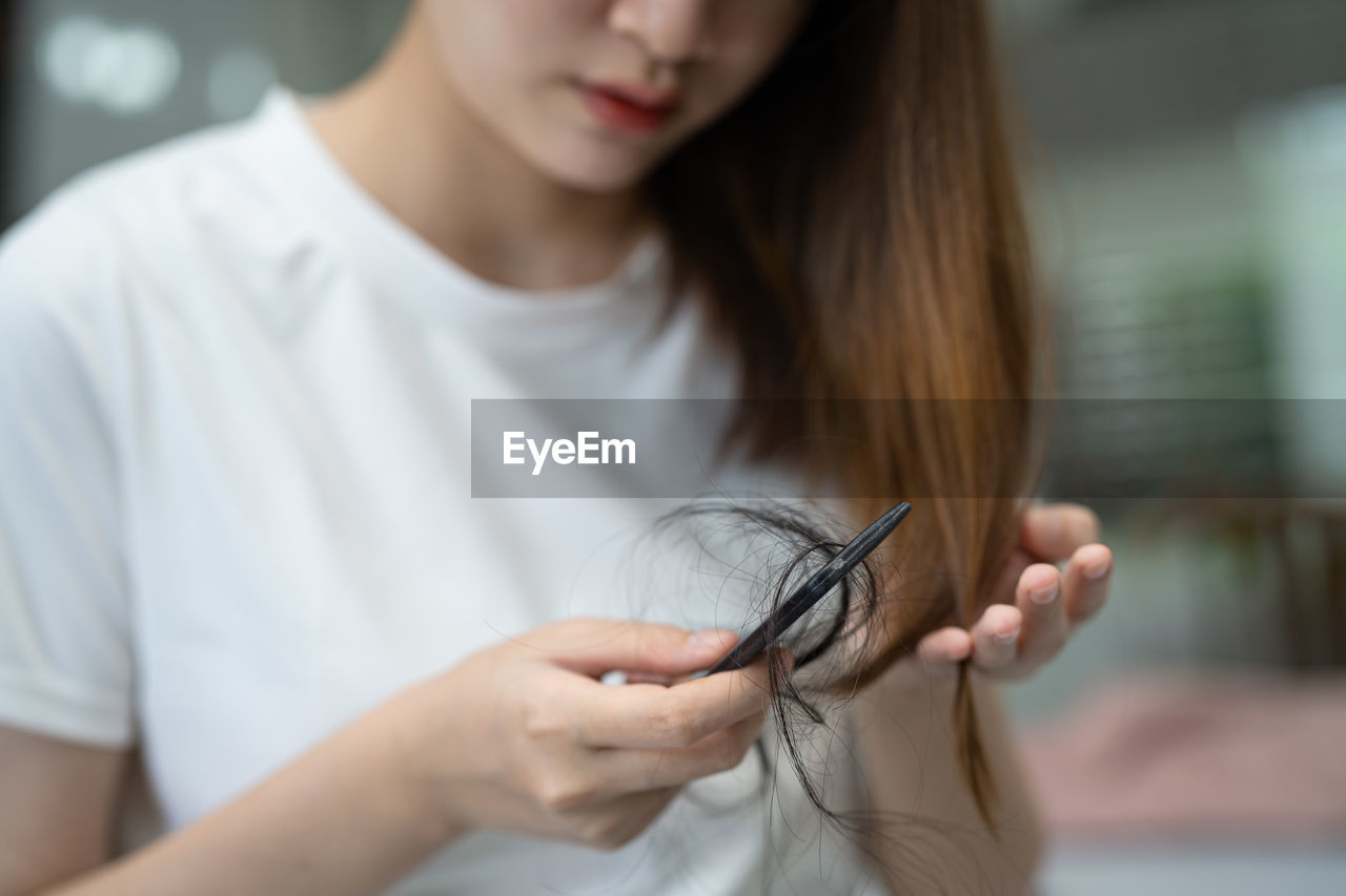 Asian woman have problem with long hair loss attach to comb brush.