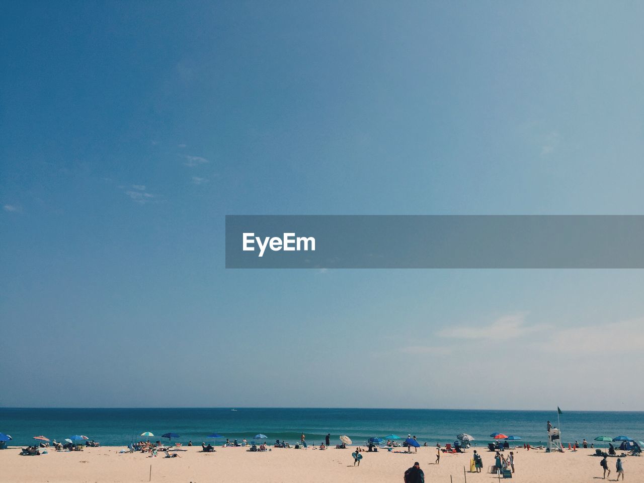 Crowd at beach against blue sky