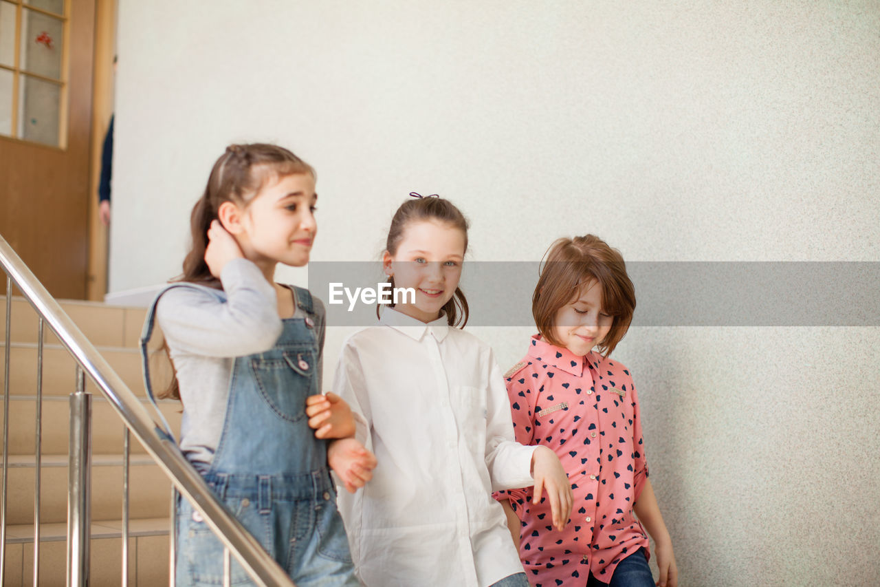Portrait of friends standing against wall