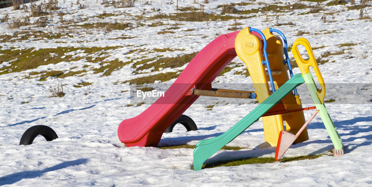 playground, nature, snow, cold temperature, winter, outdoor play equipment, day, land, no people, outdoors, sunlight, playground slide, public space, sled, leisure activity, yellow, relaxation