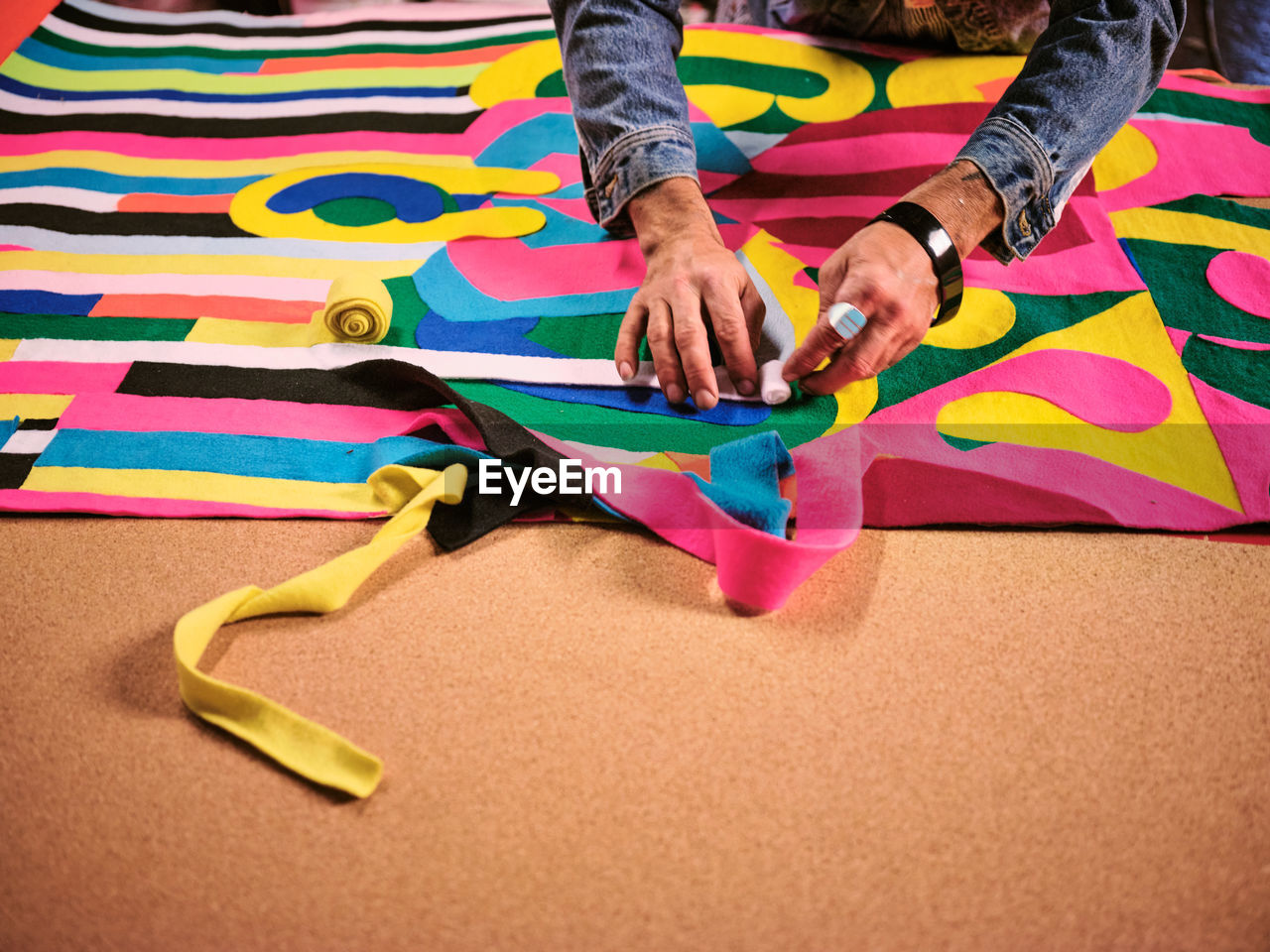 An artist works on a giant cloth tapestry in the their art studio.