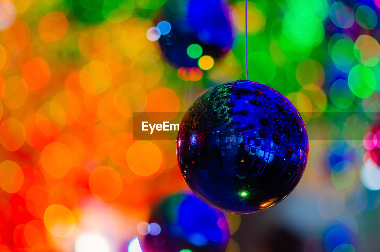 Bauble hanging to decorate for christmas holiday with colorful bokeh from light and other baubles.