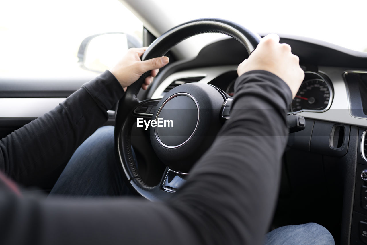 MIDSECTION OF MAN USING MOBILE PHONE WHILE CAR