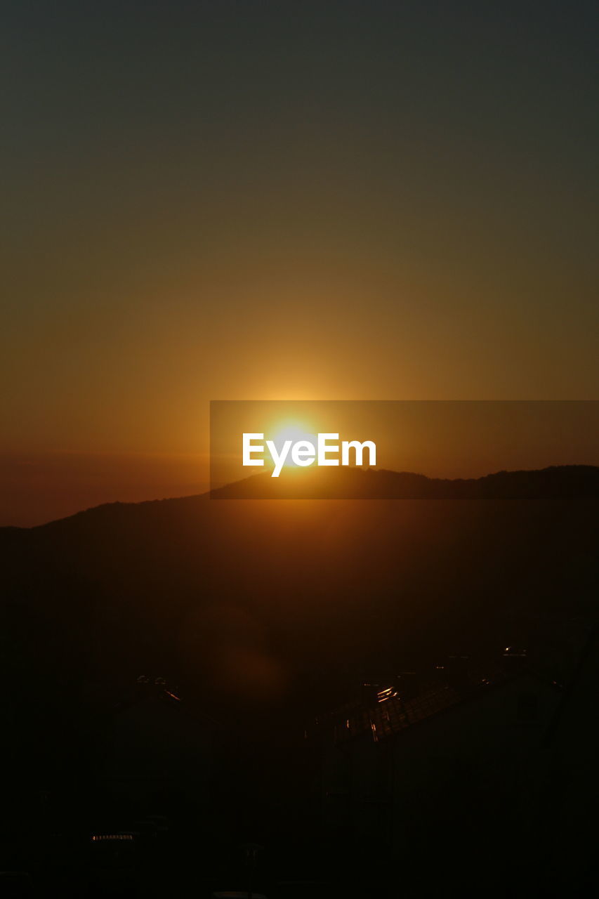 SCENIC VIEW OF SILHOUETTE MOUNTAIN AGAINST ORANGE SKY