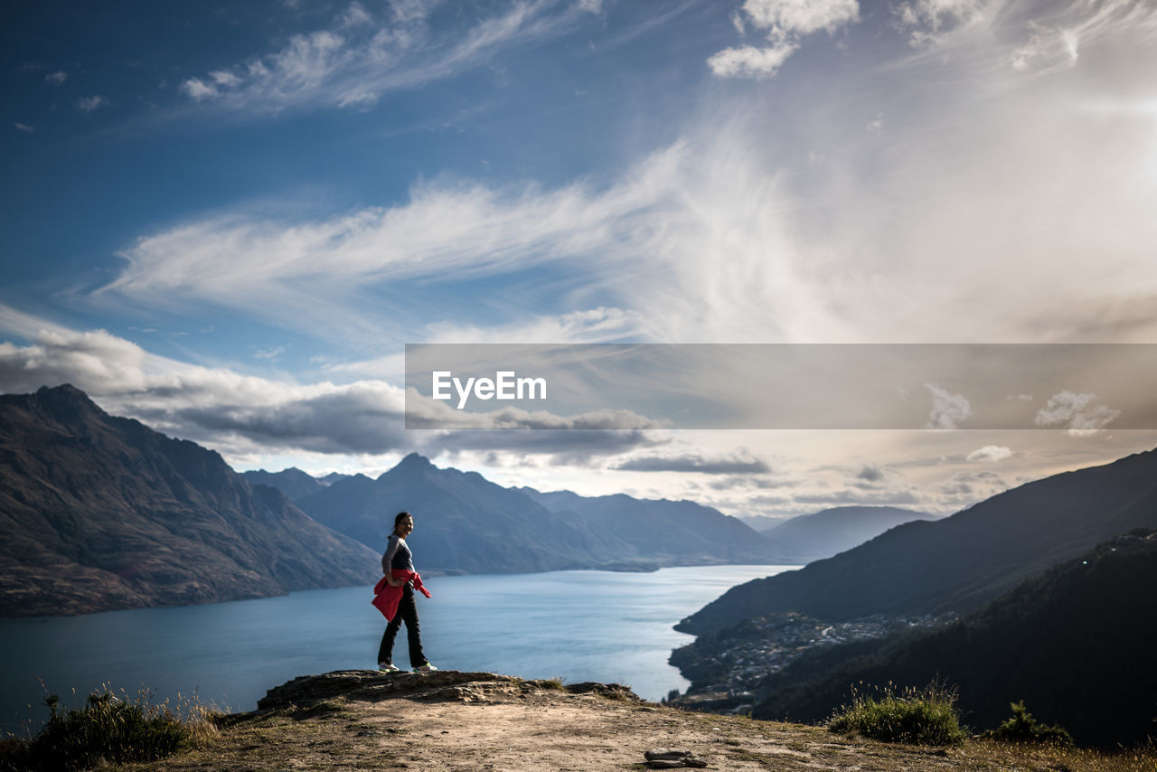 Full length of woman standing on landscape against mountains