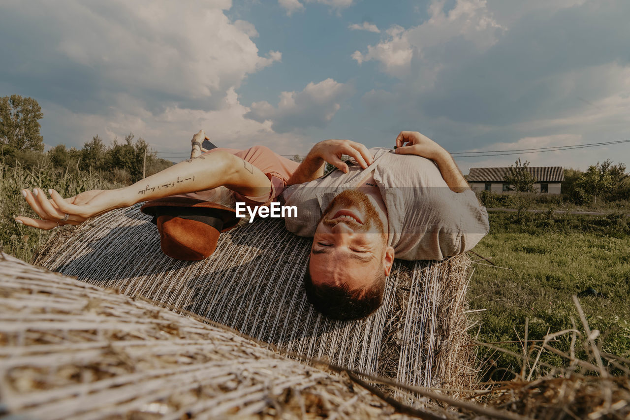 Smiling couple lying on hay bale