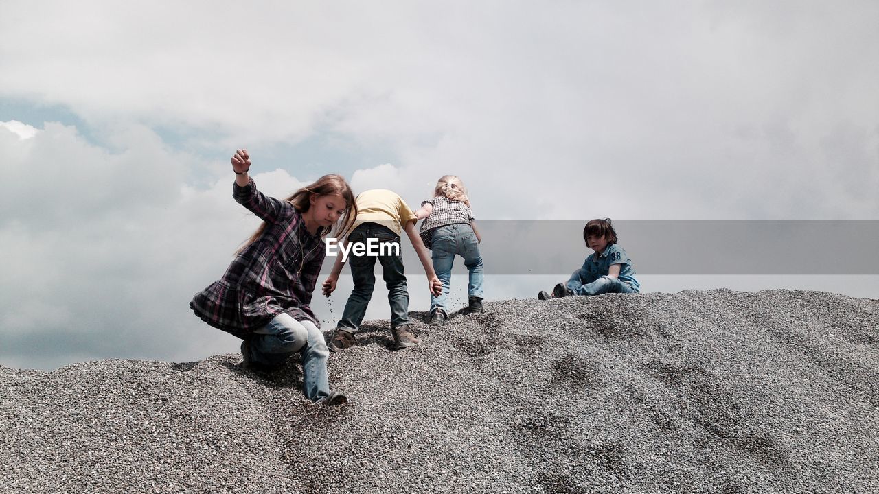 LOW ANGLE VIEW OF WOMAN AGAINST CLOUDY SKY