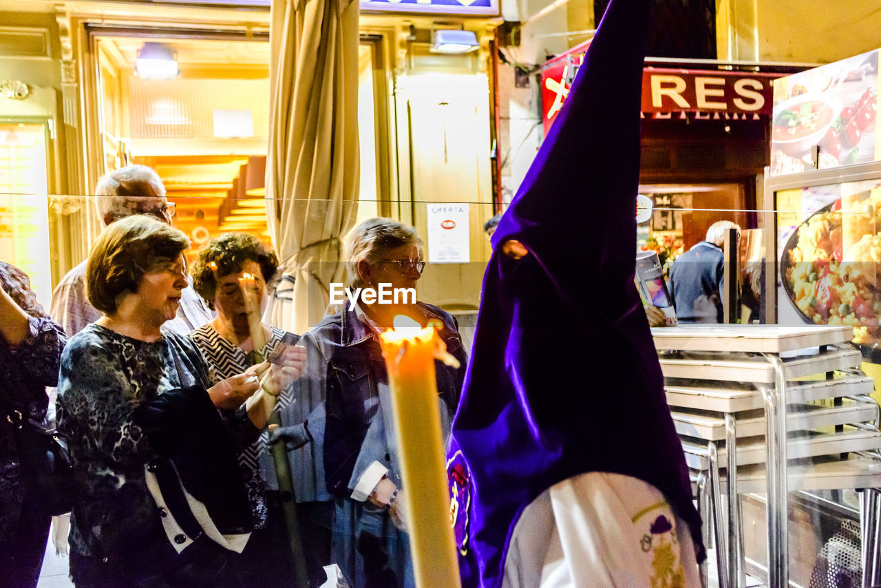 GROUP OF PEOPLE AT ILLUMINATED STORE