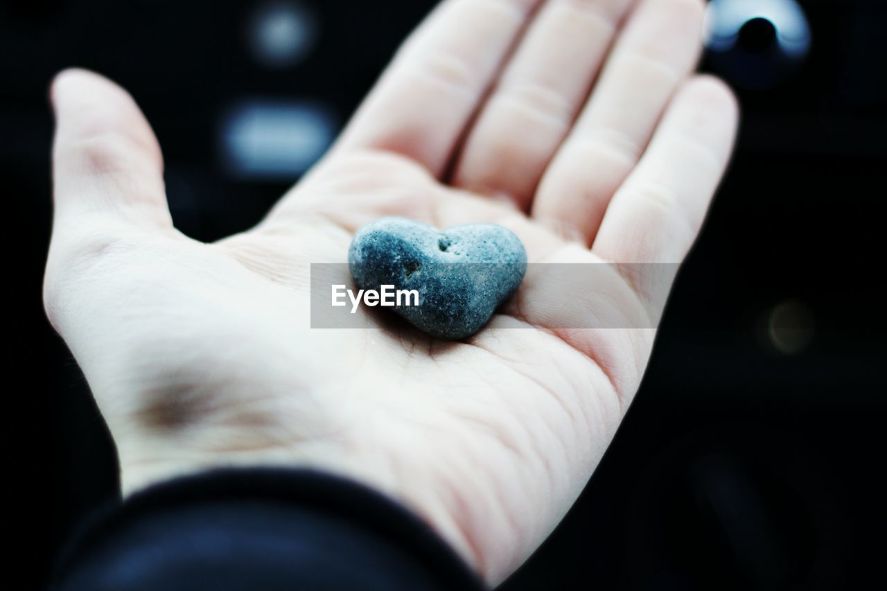 Cropped hand of person holding heart shape stone
