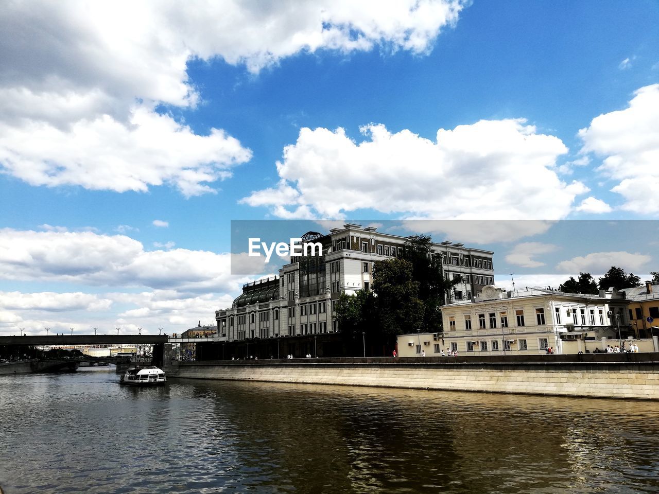 VIEW OF BUILDINGS BY RIVER AGAINST CLOUDY SKY