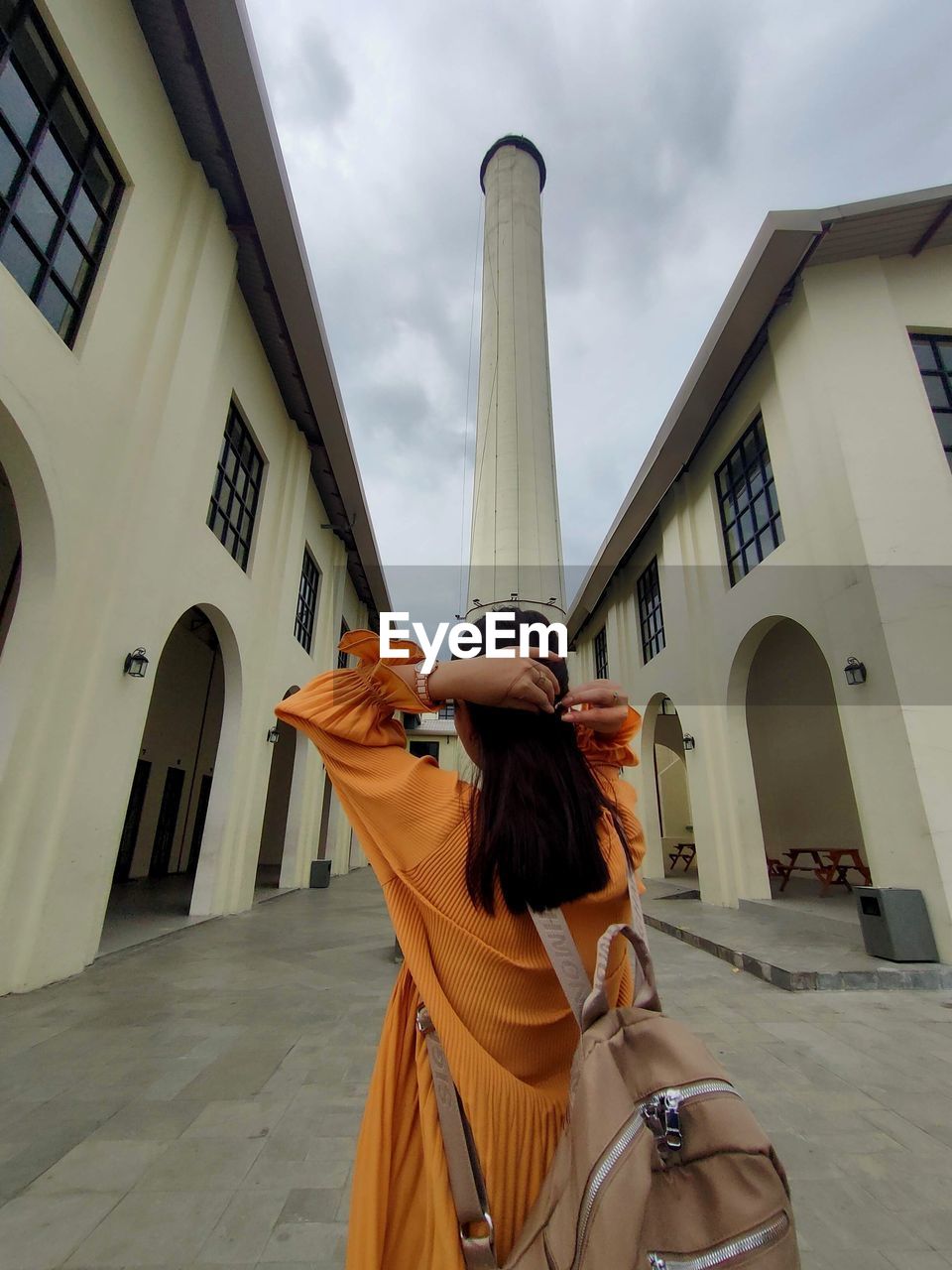 Rear view of woman standing by buildings against sky